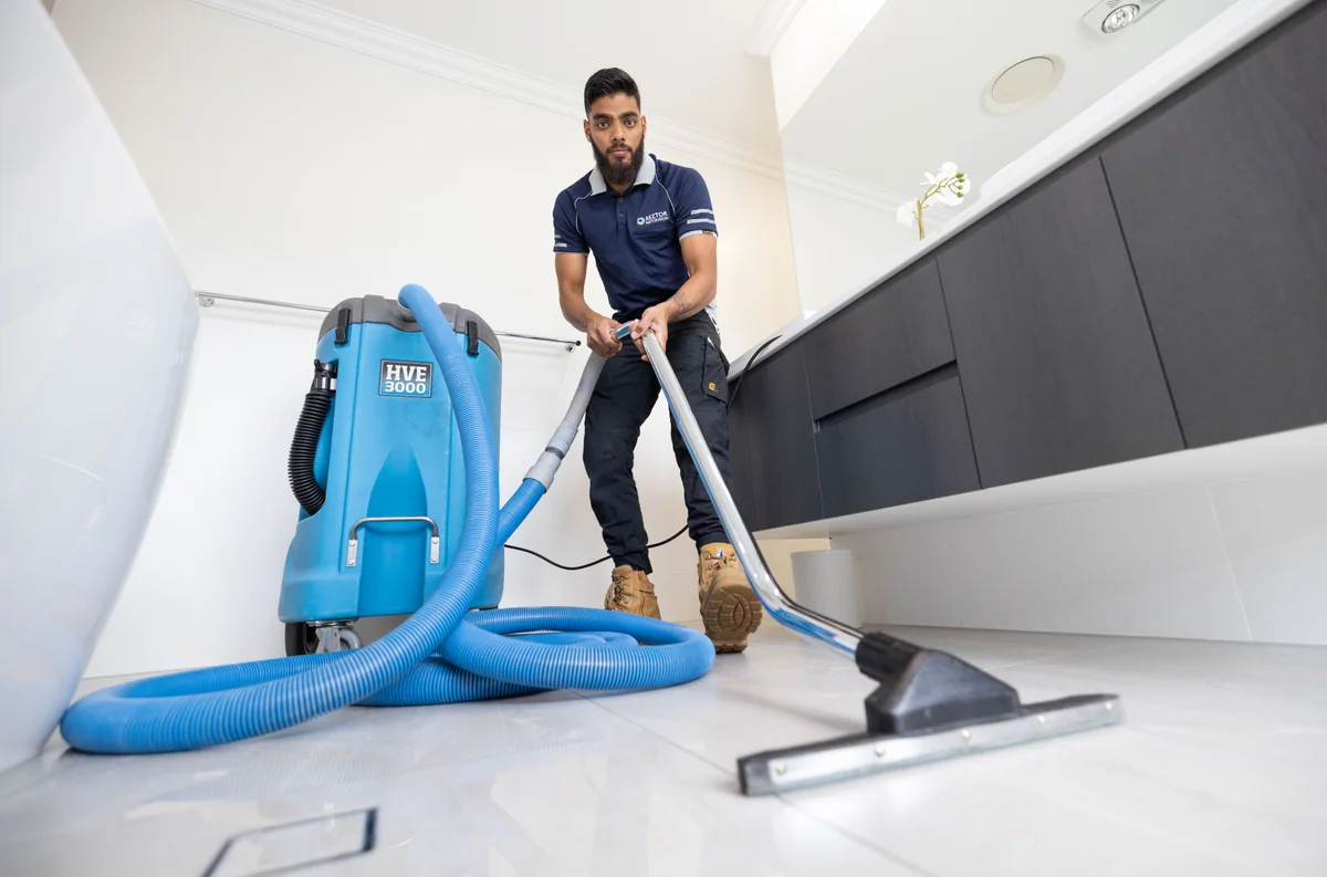 A Reztor technician using a water extraction wand and portable extraction machine.