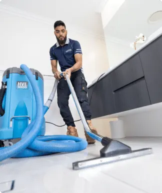 Technician using water extraction equipment on a tiled floor